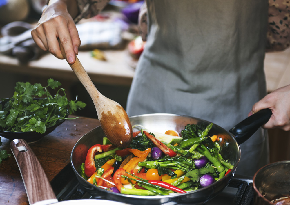 A cook roasting vegetables in a pan